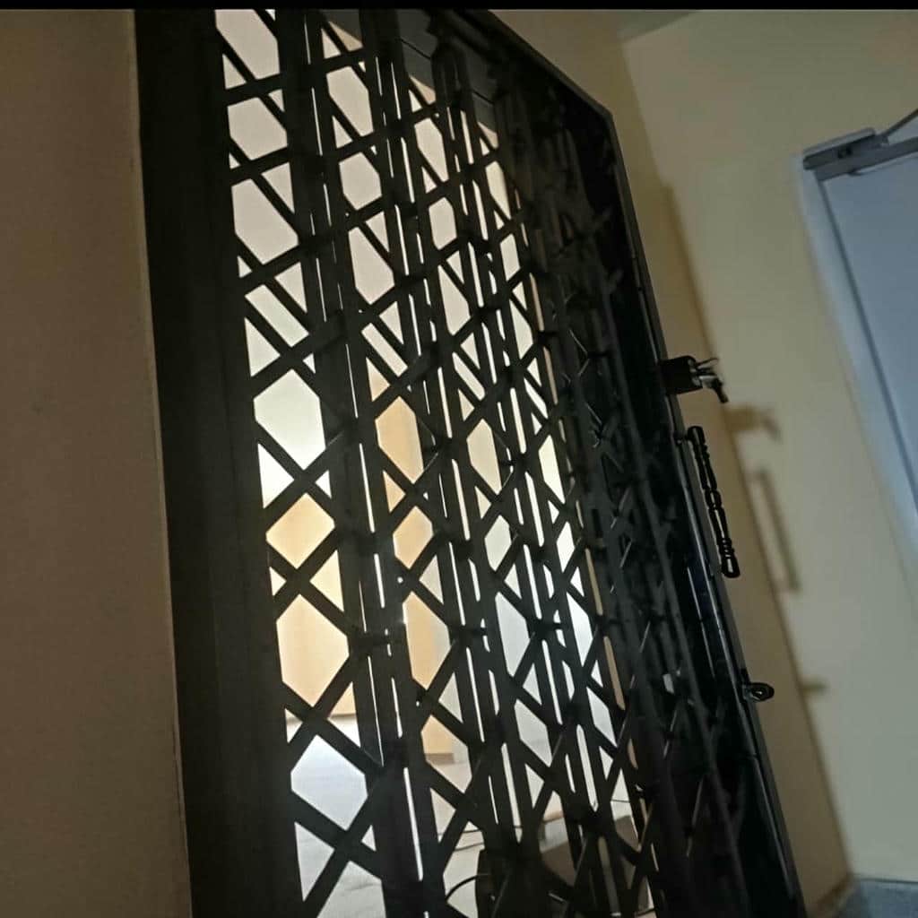 حفاظ درب آکاردئونی طوسی مقابل چارچوب سنگی
