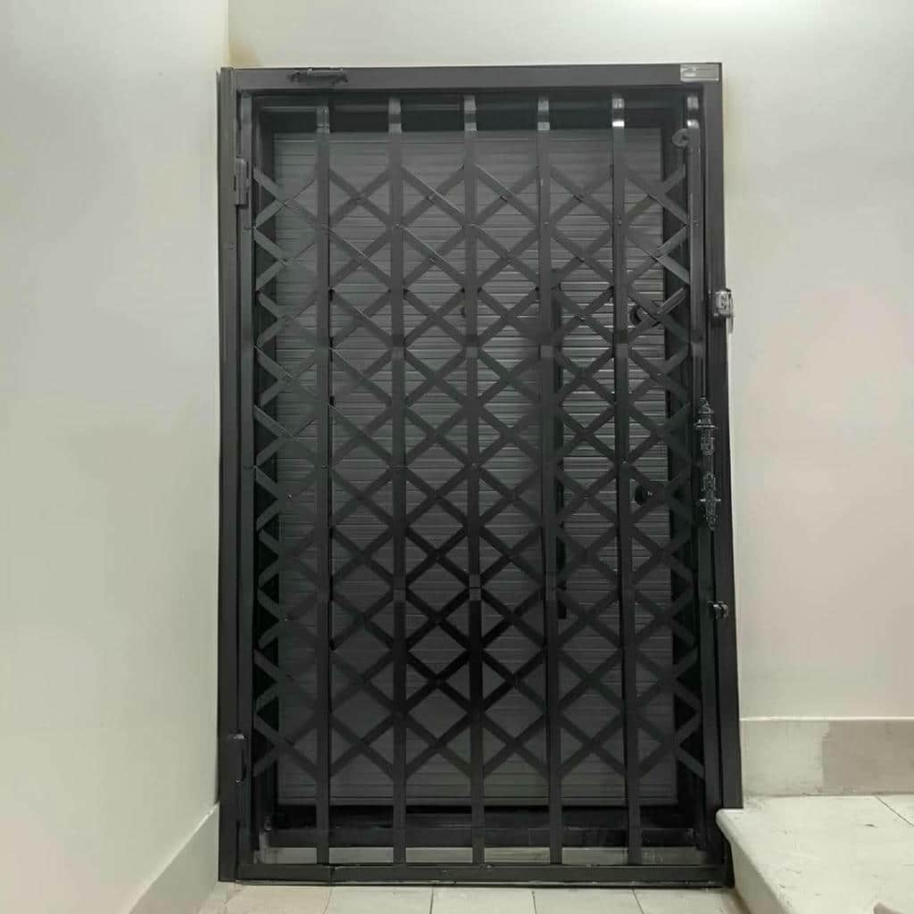 حفاظ درب آکاردئونی قهوه‌ای مقابل درب چوبی