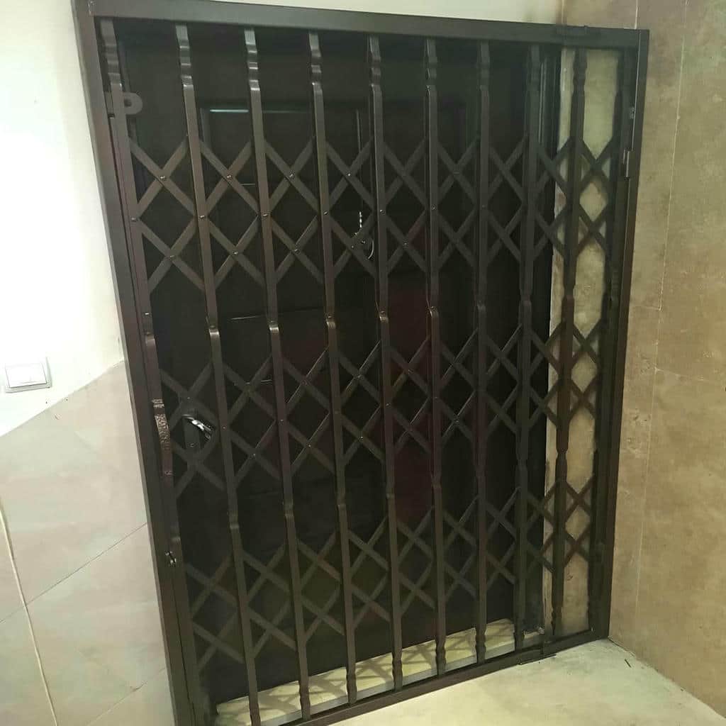 حفاظ درب آکاردئونی مشکی در حیاط آفتاب‌گیر اصفهان